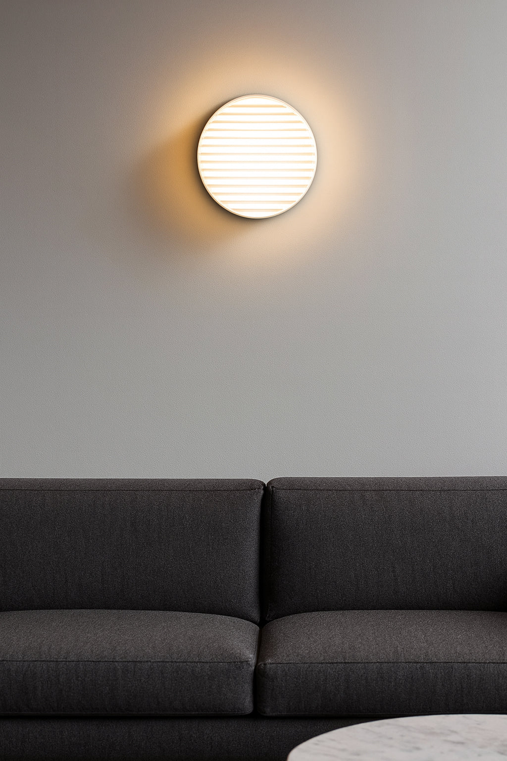 Modern wall light fixture on a gray wall above a dark gray sofa.
