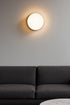 Modern wall light fixture on a gray wall above a dark gray sofa.