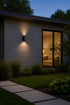 Modern house exterior with a light fixture and glass door reflecting interior.