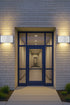 Modern front door with glass panels on a brick wall with wall lights.