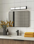 Bathroom with a mirror, sink, and yellow towels on a tiled wall.
