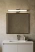 Bathroom vanity with mirror, light fixture, and toiletries against a beige wall.
