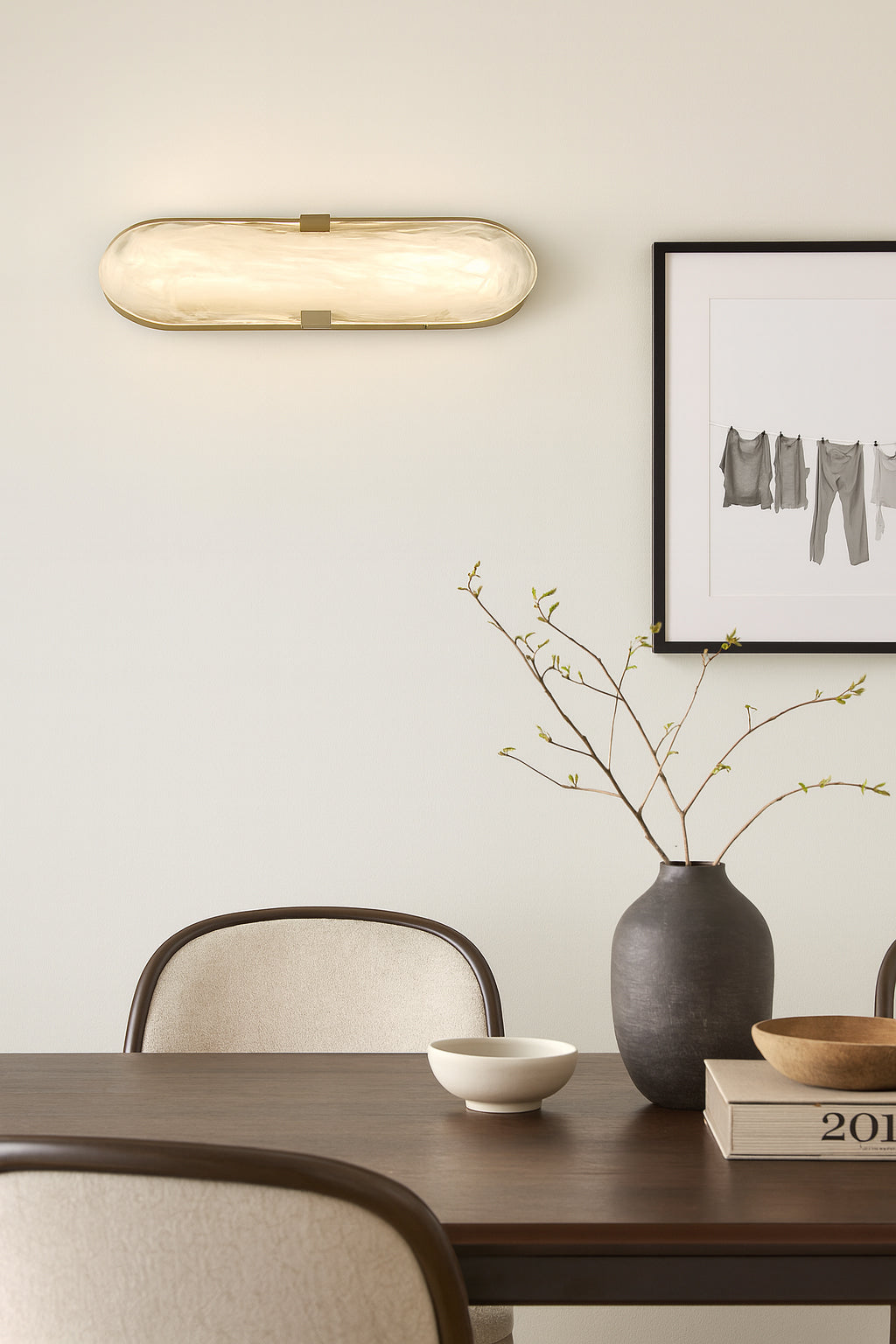 Modern interior design with a wall light fixture, vase, and decor items on a table.
