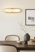 Modern interior design with a wall light fixture, vase, and decor items on a table.