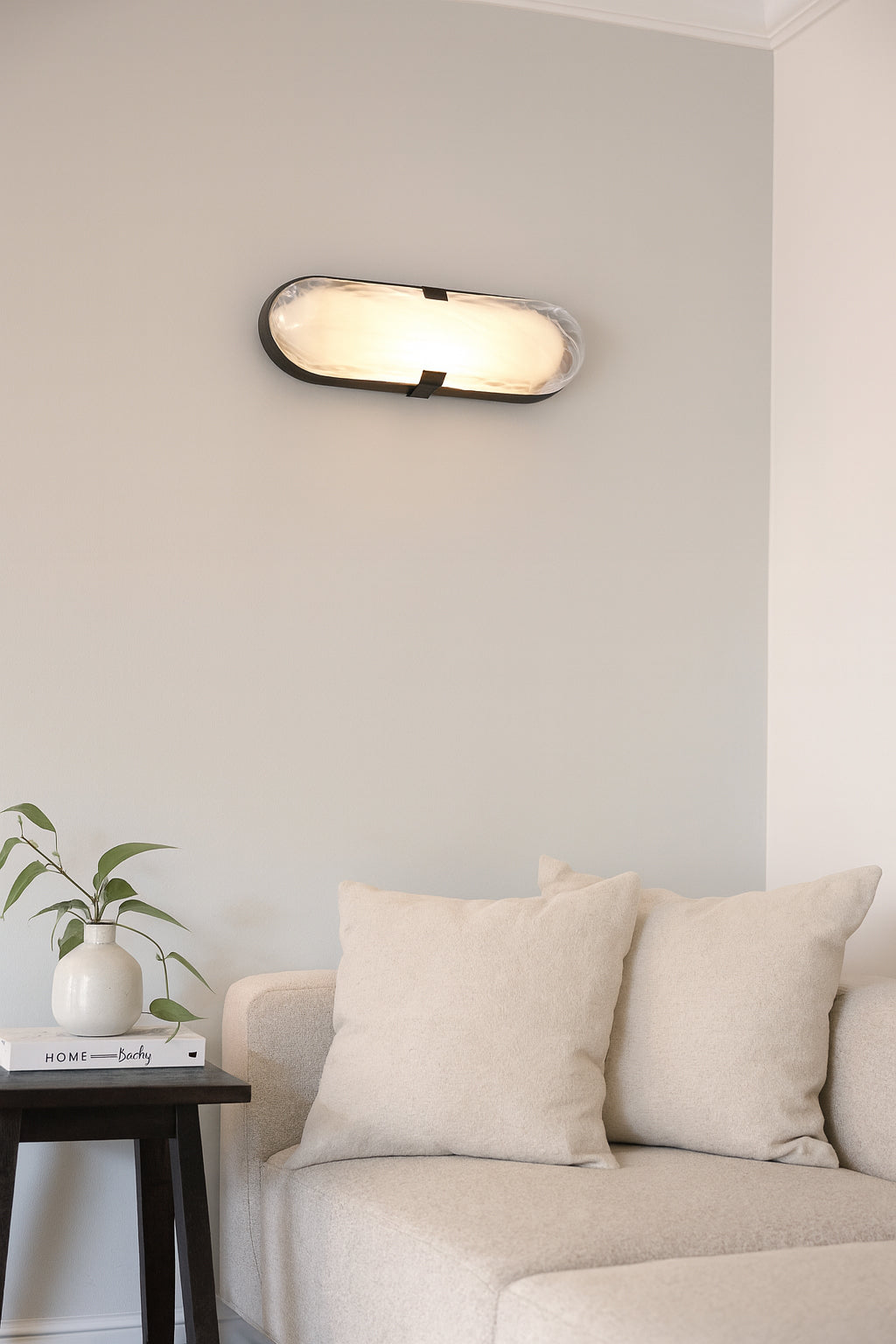 Modern wall light fixture above a beige sofa in a living room.